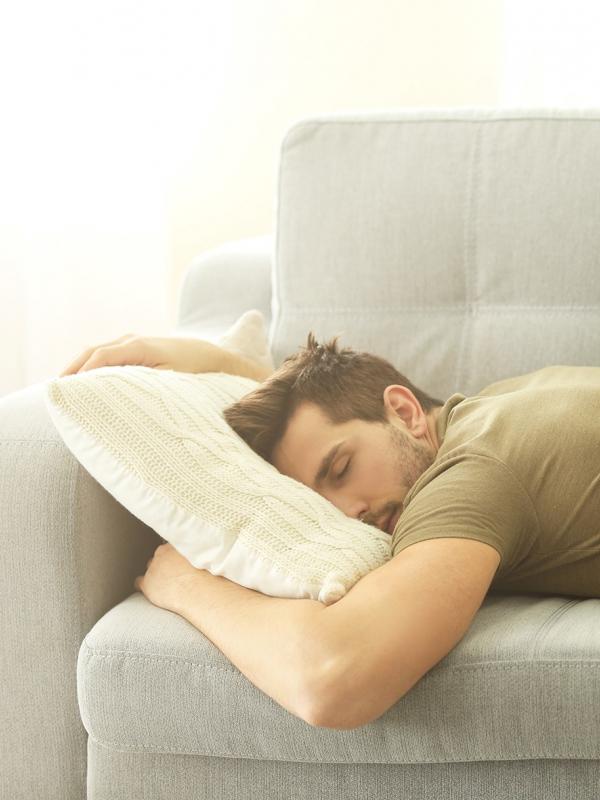 Mann schläft auf Couch ist energielos und müde