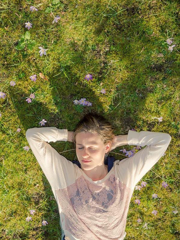 Frau liegt im Frühjahr in grüner Wiese und entspannt sich