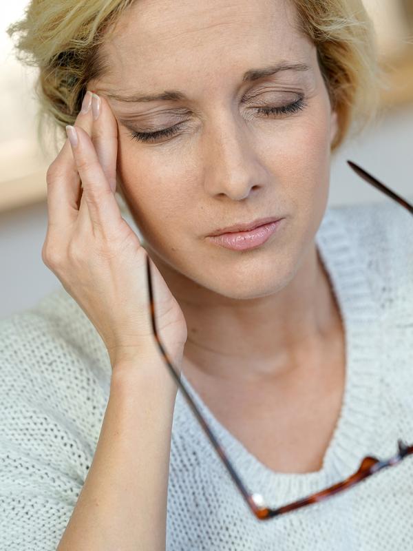 Frau hält sich schmerzverzerrt die Schläfe