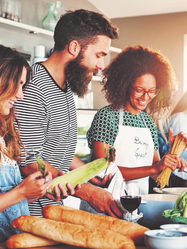 Gruppe von Freunden beim gemeinsamen Kochen von veganer und vegetarischer Gerichte