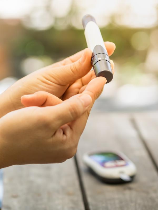 Person sticht sich in den Finger um Blutzucker zu messen