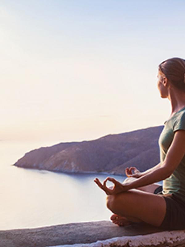 Frau meditiert an See und ist entspannt