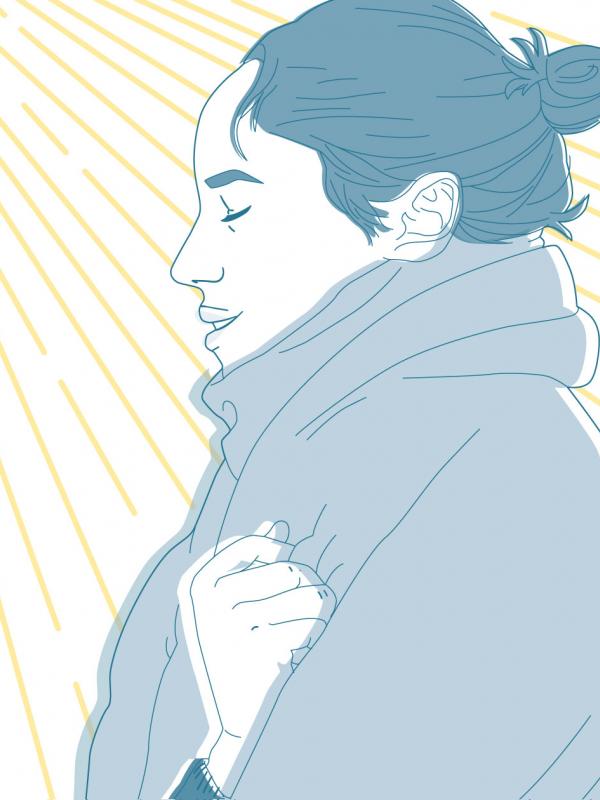 Frau eingewickelt in Schal sammelt Sonnenstrahlen bei kaltem Wetter