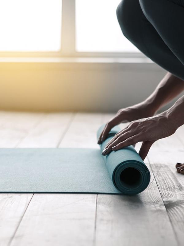 Frau rollt Yogamatte auf